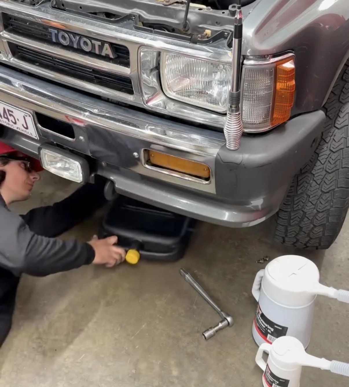 Under the front of a Toyota four wheel drive in the workshop, oil draining into a pan